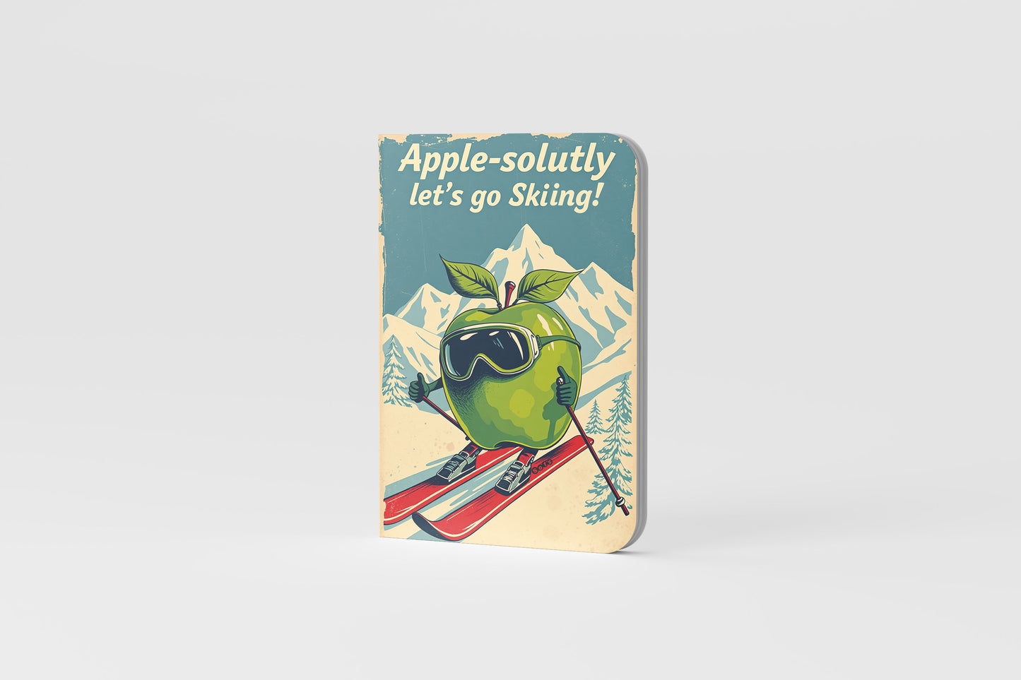 Notebook with a green apple character skiing, text 'Apple-solutely let's go Skiing!'