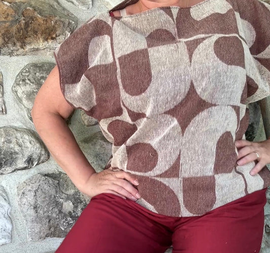A woman wearing a retro brown and beige geometric patterned short-sleeve top made from vintage beach towel
