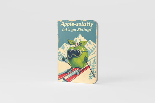Notebook with a green apple character skiing, text 'Apple-solutely let's go Skiing!' 